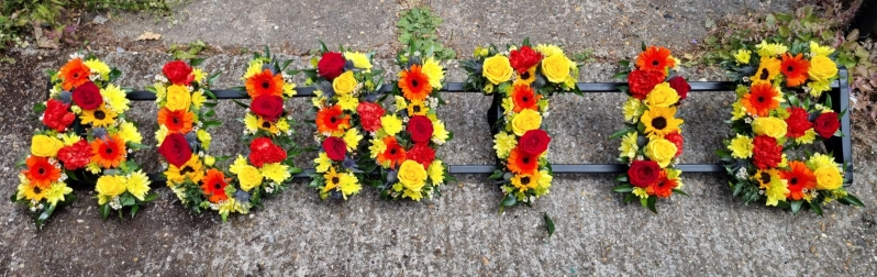 Mixed bright funeral flowers to include sunflowers and roses and fillers designed by florist in Hayes,  Bromley 