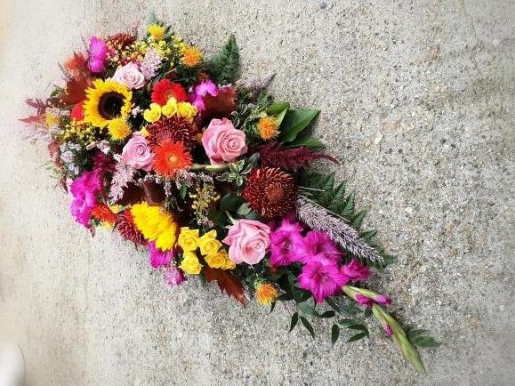 rustic funeral Teardrop spray to include sunflowers, heather, pink roses, cerise gladioli, red blooms.