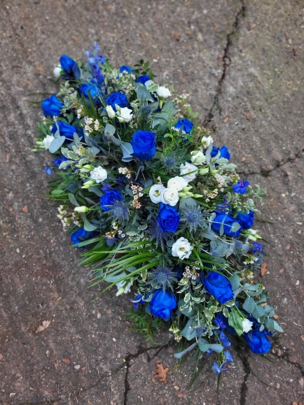 roayl blue roses coffin spray with thisle, delphiniums and white lisanthius made by florist in Bromley