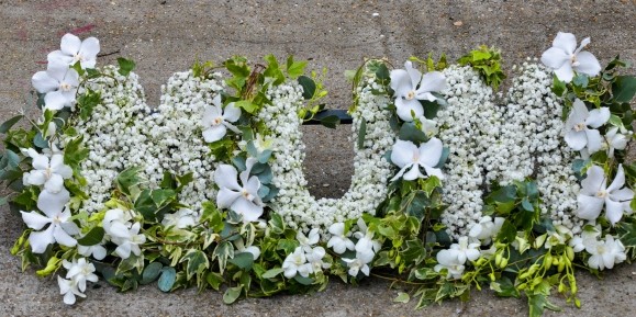 picturesque letters made with gypsophilium on bed of foliage with orchids around made by florist in Bromley for free delivery in BR1 BR2 BR£ BR4 BR5 BR6 BR7 BR8 CR0 CR2 CR3 CR4 CR5 CR6 CR7 CR8 SE12 SE3 SE9 SW16 SE25 TN16