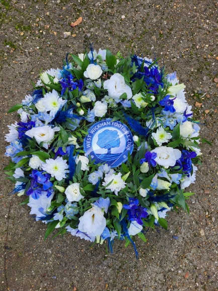 mixed flowers posy pad with a logo for a funeral by Blooms and Candy Florist