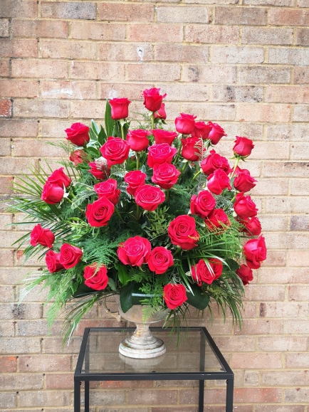 Red roses large urn funeral arrangement suitable for the service or for the church