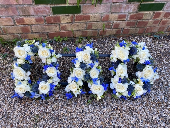 Mix of white roses, yellow spray roses, delphiniums and white fillers. By Blooms and Candy Funeral Florist Bromley