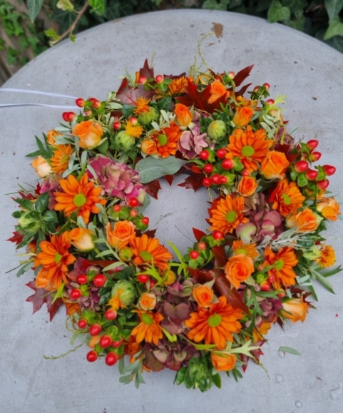 Autumnal funeral wreath with orange flowers by Funeral Florist Bromley 
