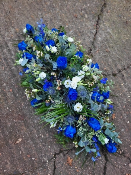roayl blue roses coffin spray with thisle, delphiniums and white lisanthius made by florist in Bromley