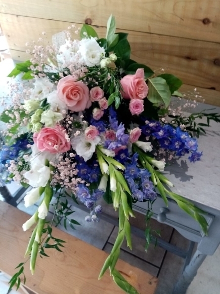 beautiful composition of white long flowers with blue delphiniums and soft pink roses by Blooms and Candy funeral floriist Bromley and Beckenham