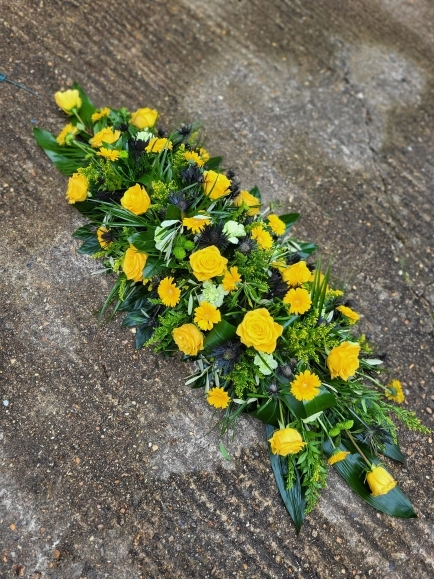 Jamaican flag coffin spray for a funeral made by Blooms and Candy Florist