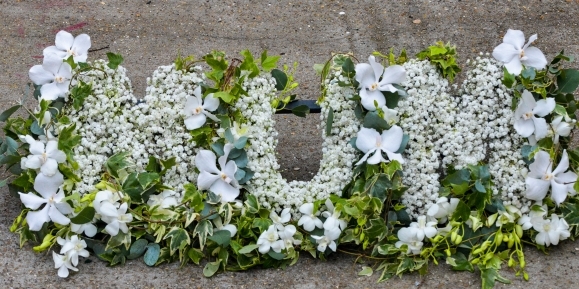 picturesque letters made with gypsophilium on bed of foliage with orchids around made by florist in Bromley for free delivery in BR1 BR2 BR£ BR4 BR5 BR6 BR7 BR8 CR0 CR2 CR3 CR4 CR5 CR6 CR7 CR8 SE12 SE3 SE9 SW16 SE25 TN16