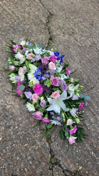Mixed lilac flowers coffin spray by Blooms and Candy Florist