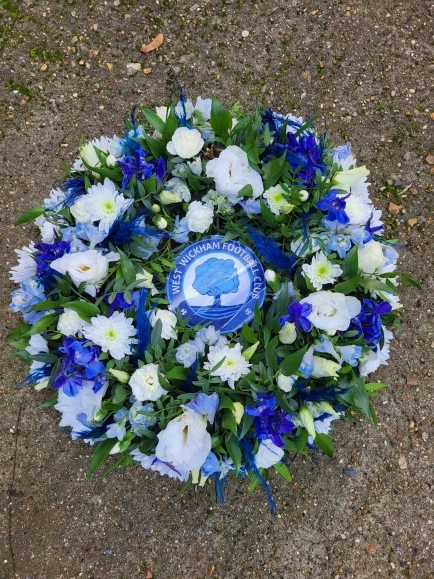 mixed flowers posy pad with a logo for a funeral by Blooms and Candy Florist